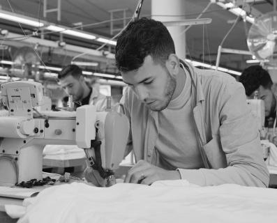 Hombre trabajando en una máquina de coser en una fábrica textil proveedora de Inditex
