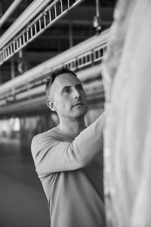 A warehouse worker at a logistics platform adjusts a garment hanging on the order sorting carousel