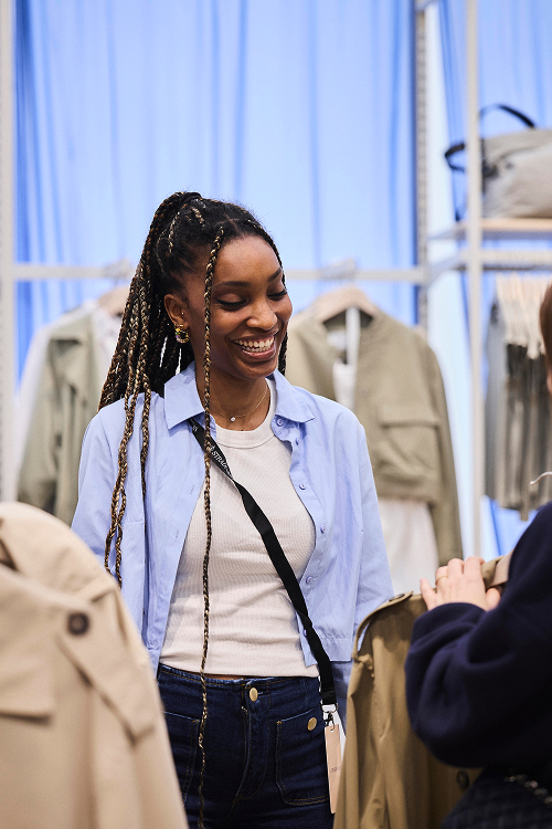 A sales assistant at a store smiles at a customer as she answers her questions about a garment