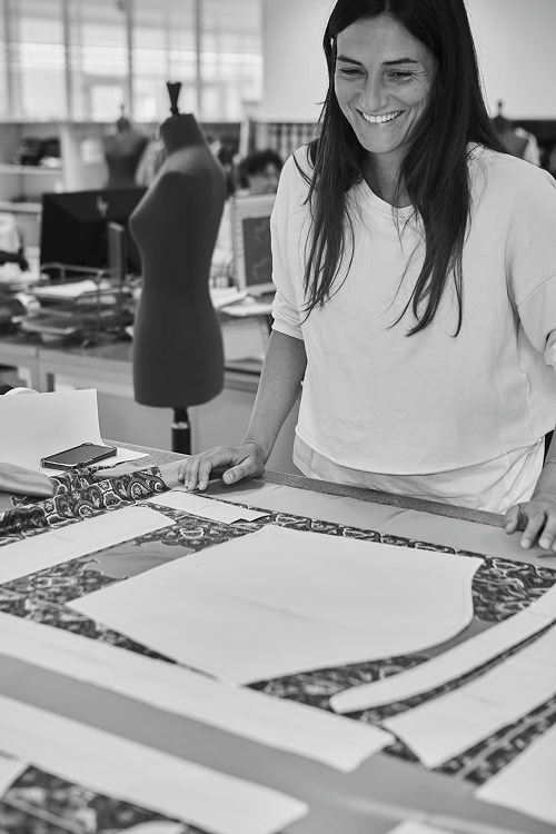 A pattern maker checks the paper pattern pieces positioned on the fabric before cutting it