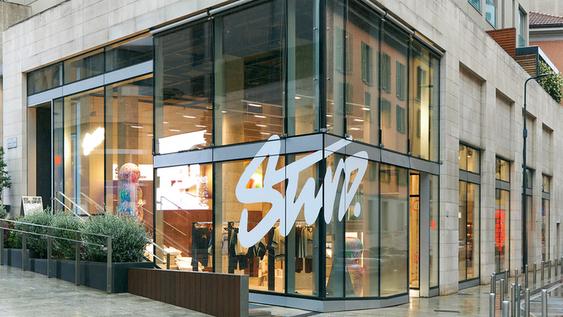 Glass facade of the Pull and Bear temporary store with the white logo ''STWD'' in the corner, showing clothes inside.
