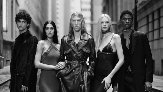 Designer Ludovic de Saint Sernin poses with four models on a city street.