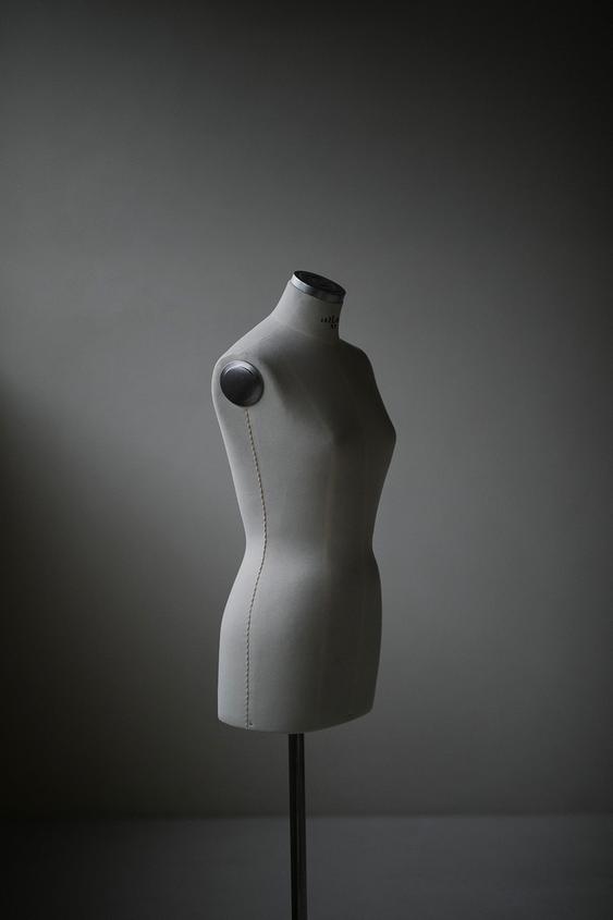 Gray fabric tailor mannequin on dark background.