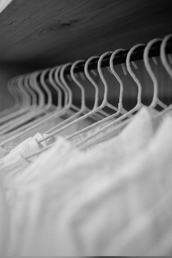 White hangers with clothes in a wardrobe,