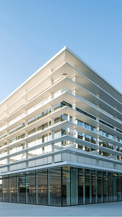 Photo of Inditex headquarters, a modern building of glass and white structures under a blue sky.