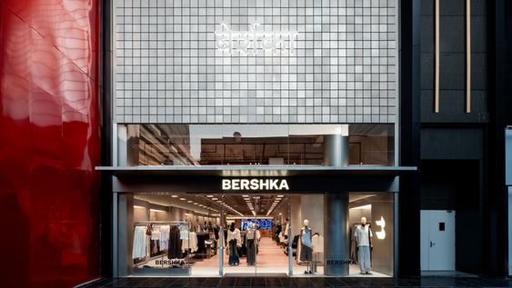 Front of the Bershka store with a large shop window, mannequins and clothes on display, and a reflective red wall on the left.