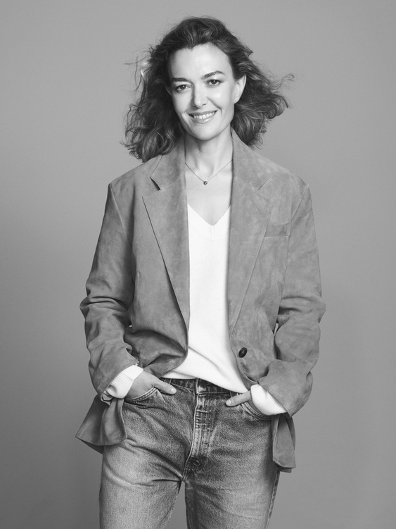 Portrait of Marta Ortega, chairperson of the Inditex Group, wearing a blazer and jeans, with her hands in her pockets.