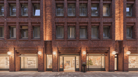 Brick facade of a building with the Zara Home store illuminated on the ground floor and windows on the upper floors.
