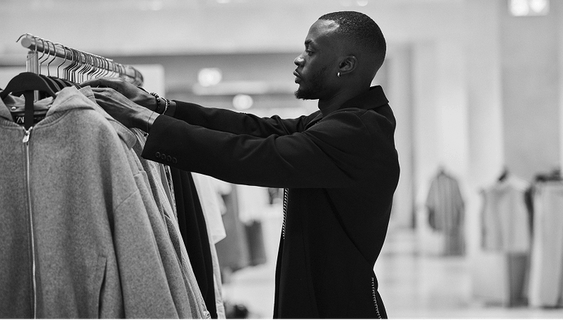 A shop assistant checks several garments on a clothing rack.